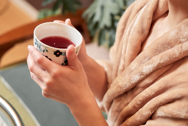 バスローブ姿で温かい飲み物を飲む女性