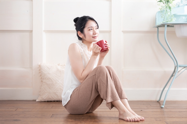 床で飲み物を飲む女性