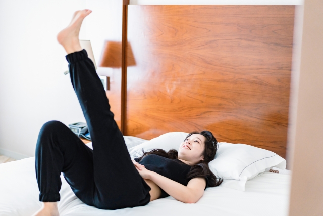ベッドの上で寝ながらストレッチをする女性