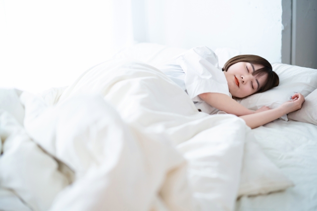 白い寝具に包まれ気持ちよさそうに眠る女性